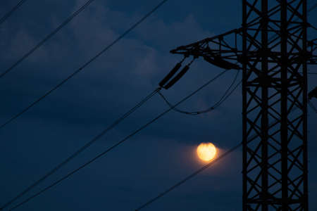 power line against the background of the moon in the sky at sunset at night in Ukraine, the night sky and the moon the city of Dniproの写真素材
