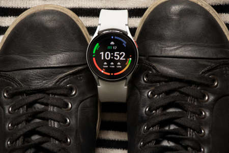 Ukraine Dnipro 11/30/2021 - Smart watch Samsung Galaxy 4.40 mm and a mobile phone with an application for Samsung and sports women's shoesのeditorial素材