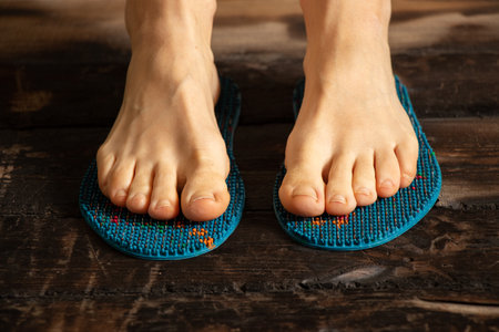 massage insoles with needles for healing and relaxation on the girl's feet on the floor of the...