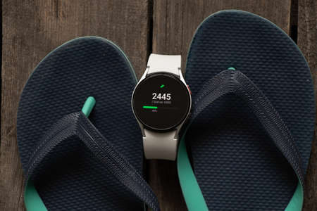 Ukraine Dnipro 11/30/2021 - Smart watch Samsung Galaxy 4.40 mm next to beach shoes at sea, rest at seaのeditorial素材