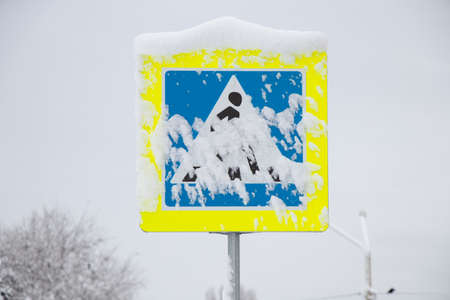 A sign of a pedestrian crossing in winter in the snow in the city drove roads in winter in Ukraine in the city of Dnipro, a pedestrian crossing road signの写真素材