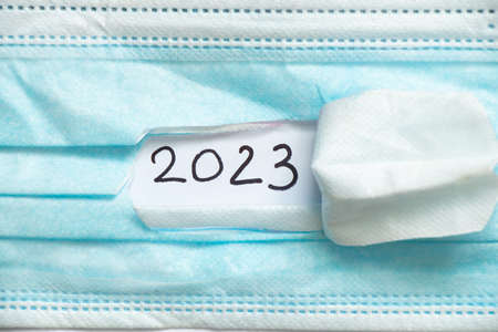 2023 written on paper on a torn medical mask, happy new year 2023, health care, holidays and medicineの写真素材