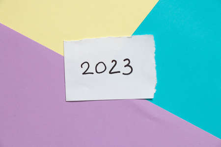2023 written on a white card that lies on colored paper, happy new year 2023