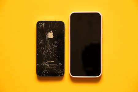 Ukraine Dnipro 06.01.2021 - Apple iPhone 12 and broken iPhone 4 on orange background, phone replacementのeditorial素材