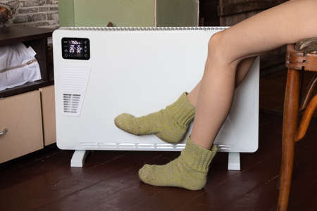 the girl's legs took the battery at home in the apartment, a warm battery and legsの写真素材