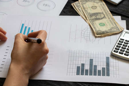 reports and histograms on paper on the table in the hands of a girl, analytics and statistics on...