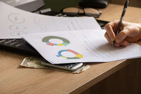 reports and histograms on paper on the table in the hands of a girl, analytics and statistics on...