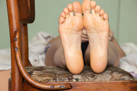 female feet on a chair at home, on vacation, bare feet at home on a chair