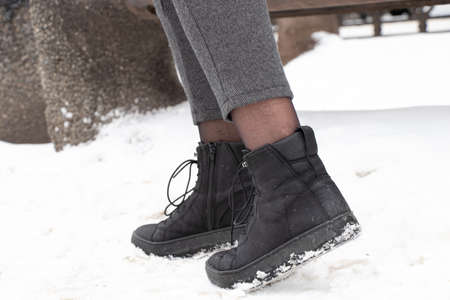 women's legs in boots in the winter on the street in the city, women's boots on the snow