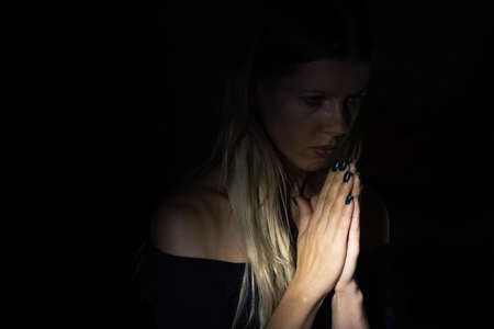 young girl praying to god in the dark, young girl in the dark, religion and people, prayerの写真素材