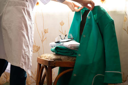 the doctor folds the medical uniform on the table in the office, medicine and health, medical uniformの写真素材