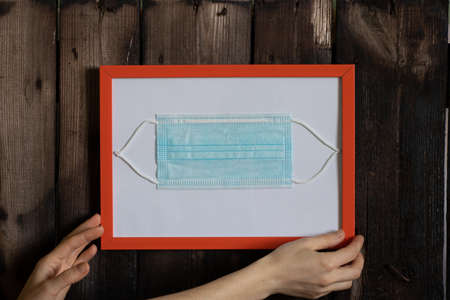 medical mask in a frame on an old wooden wall, a picture for the memory of the world pandemic 2019
