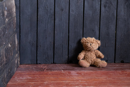 the teddy bear lies in the bedroom in the corner on the wooden floor, the bear is on the floor of the houseの写真素材