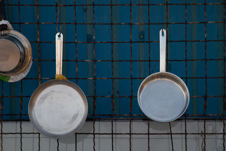 cast iron pans hang on grates on the wall, kitchen utensils are new and cleanの写真素材