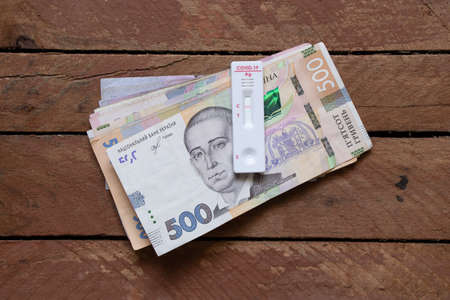 covid test lies on Ukrainian money on an old wooden table, an antibody test