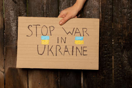 Stop the war in Ukraine written on a sign that a woman holds in her hands from her house in the Dnieper, protest action, martial law in Ukraineの写真素材