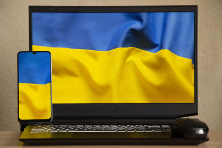The national flag of Ukraine is yellow-blue as a background on the phone and laptop, peace in Ukraine, no war, free country Ukraineの写真素材