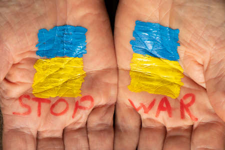 On the hands of the old woman is drawn the yellow-blue flag of Ukraine and the words stop the war, Stop the war and patriotism, peace in Ukraine, stop the war in Ukraine. Peace to all, the flag of Ukraine. Protestの写真素材