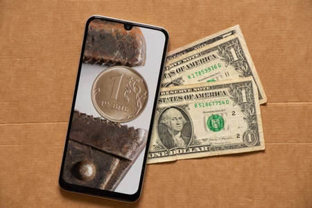 The gas key holds the Russian ruble as a background in the phone and dollars lie nearby, the collapse of the ruble, sanctions against Russia, the economic crisis in Russia and losses, newsの写真素材