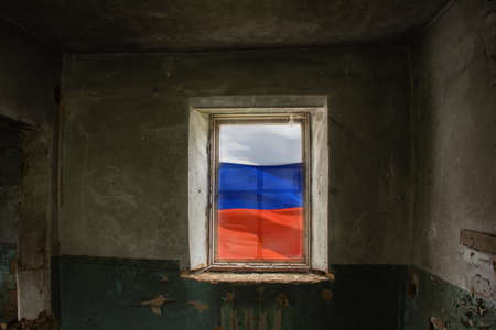 Old destroyed house with a window in which the Russian flag of Russia, Destroyed houses in Ukraine by Russian troops, the war in Ukraine 2022の写真素材