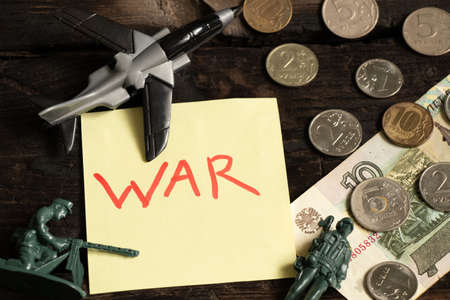 Russian money and children's military soldiers and a plane lie on the table next to it lies a piece of paper with the text war on the table, sanctions against Russia, the aggressor is tryingの写真素材