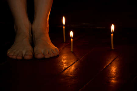bare female feet on the floor at home in the dark near candles, female feet and fearの写真素材