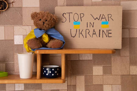 Stop the war in Ukraine je written on sign that stands on shelf home in Ukraine near a teddy bear. Peace in Ukraine. Protestの写真素材