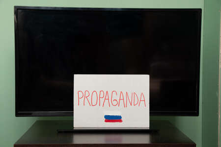 The word propaganda and the flag of Russia is written on a plate that hangs on the TV, Russian propaganda be careful, stop the war in Ukraineの写真素材