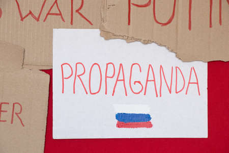 Paper signs with slogans stop war, propaganda and the Russian flag on a red background, a protest action 2022の写真素材