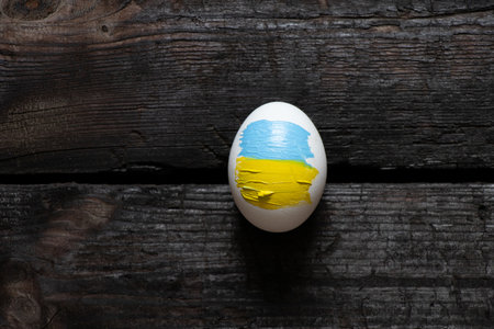 Chicken egg with the flag of Ukraine on a wooden background. Ukraine during the war, protest action, no war, peace in Ukraine 2022の写真素材
