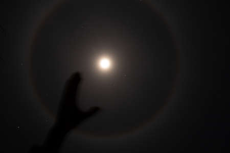 The halo phenomenon on the moon over Ukraine at night and the girl's hand 2022, the night moon and...