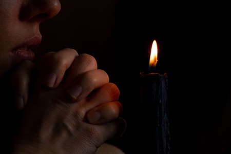 A young Ukrainian girl prays near a candle for Ukraine in Ukraine, a girl poured candles in the dark close-upの写真素材