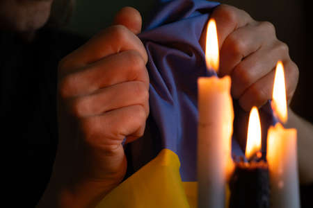 The girl holds in her hands the national flag of Ukraine, a candle, a war in Ukraine, a prayer for her country, there is no war, peace to all. Stop War 2022の写真素材