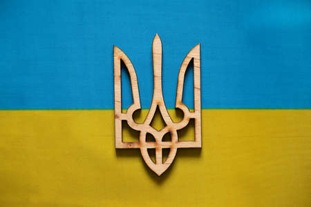 Yellow and blue national flag of Ukraine and wooden coat of arms as a background, stop the war and peace in Ukraine, peace to the people and freedomの写真素材