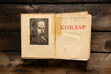 Ukraine Dnepr 15.03.2022 - An old book of kobzar poet Taras Shevchenko lies on an old wooden tableのeditorial素材