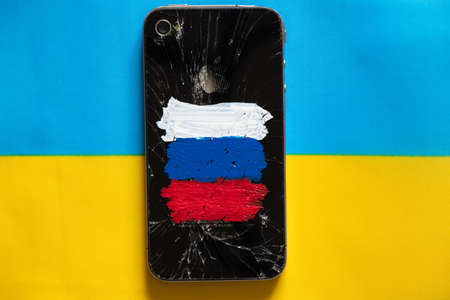 Ukraine Dnipro16.03.2022 - Broken iPhone 4 apple with the flag of Russia painted, sanctions in Russia, the war of Russia against Ukraine, the financial crisis in the country 2022のeditorial素材