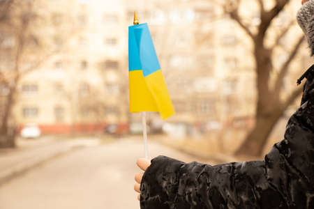 Ukrainian child in his hand holds the national flag of Ukraine in the city of Dnipro during the war with Russia, stop the war in Ukraine 2022の写真素材