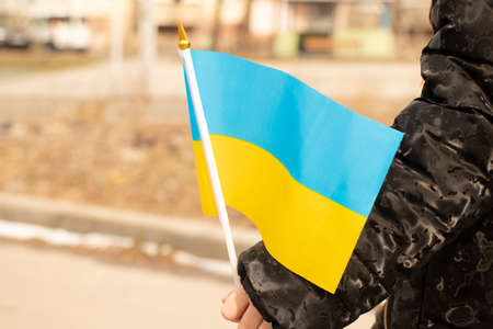 Ukrainian child in his hand holds the national flag of Ukraine in the city of Dnipro during the war...