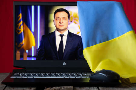 Ukraine Dnipro 19.03.2022 - Portrait of the President of Ukraine Volodymyr Zelensky on a laptop as a background and the flag of Ukraine at home.Newsのeditorial素材