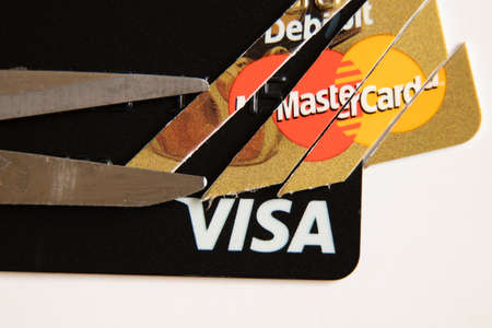 Ukraine Dnipro 01.04.2022 - Two Visa and Mastercard bank cards on a white background, one card is cut with scissors, sanctions, disconnection from swift Russiaのeditorial素材