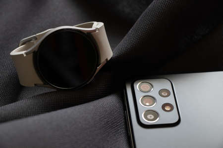 Ukraine Dnepr 10.04.2022 - Samsung A52 smartphone and smart watch Samsung Galaxy Watch 4 on gray fabric, buying new gadgets, macro photo, camera on the phoneのeditorial素材