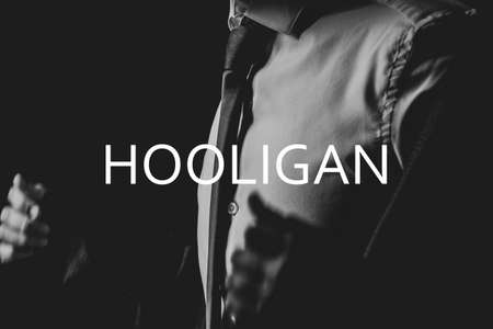 Young man takes off his jacket in the dark, men's suit, text hooligan