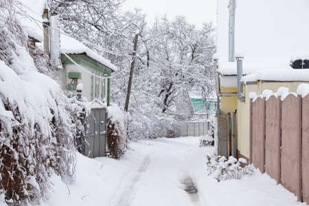 Street in the snow with one-story houses in the snow and roads along the street in Ukraine in the...