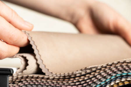 A catalog of different colors of fabrics in the hands of a girl for the choice of a client for upholstery, examples of multi-colored fabrics as a background, fashionable fabricsの写真素材