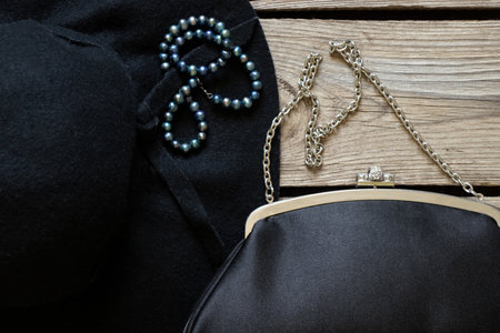 Black women's hat and a black evening bag and a number of pearl beads on a wooden table, fashion and trend, beauty and accessoriesの写真素材