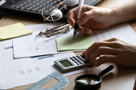The girl sits at her desk and draws up graphs and histograms about income, business and finance,...