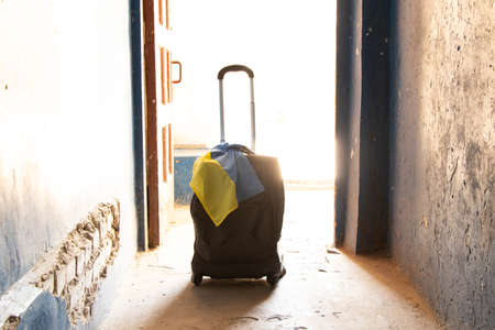 A suitcase with the flag of Ukraine stands in the entrance of the house, people leave their homes because of the war, Ukrainian refugees, the war in Ukraine, a suitcase and travelの写真素材