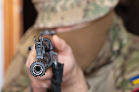 A Ukrainian soldier in military uniform holds a machine gun, the war in Ukraine and the protection of his home and family 2022の写真素材