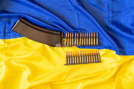 Bullets in the horn lie on the yellow-blue flag of Ukraine, war in Ukraine, defense of the motherland, weapons, bullet 2022の写真素材