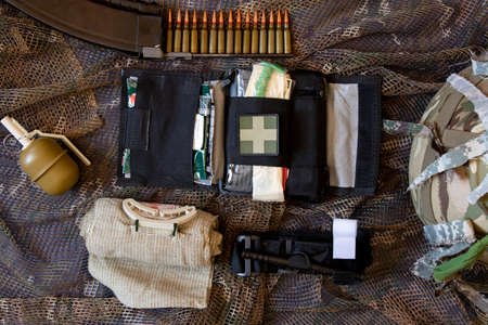 Ukraine Dnipro 09.05.2022 - A first aid kit of a military soldier and a grenade a bullet in a horn and a helmet in Ukraine in the war lies on a camouflage net, an ambulance, a military weaponのeditorial素材